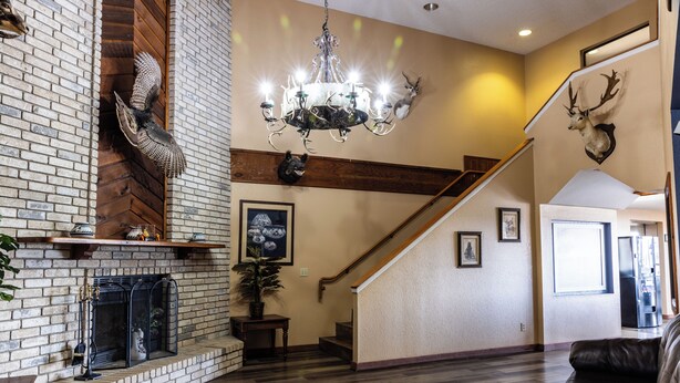 A spacious living room with a fireplace, a chandelier, and a staircase. - Boerne Inn and Suites (Boerne)