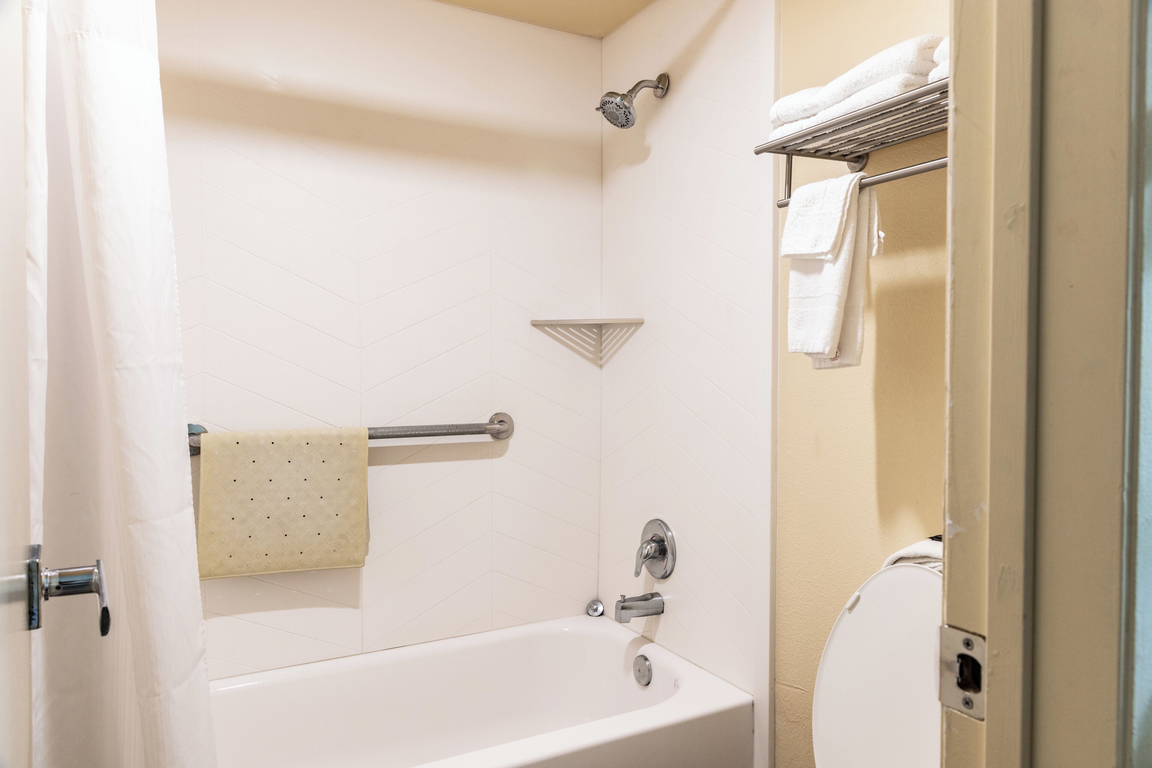 A bathroom with a bathtub, a showerhead, a towel rack, and a toilet.