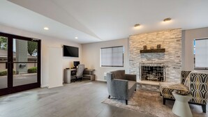 A modern living room with a stone fireplace, a grey sofa, and a patterned armchair.