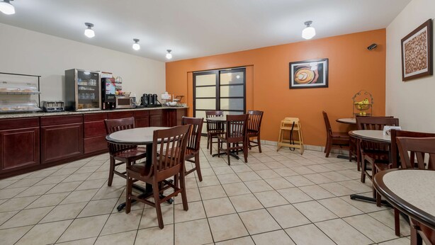 A restaurant with a kitchen area, multiple tables and chairs, and a large window. - Best Western Sunrise Inn (Eagar)