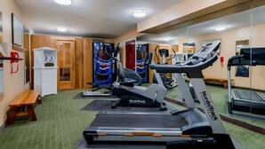 A gym with treadmills, exercise bikes, and a mirrored wall.