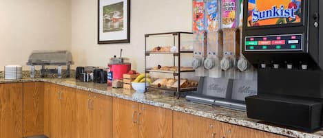 A breakfast bar with a coffee machine, a juice dispenser, and a selection of cereals.