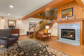 Cozy living area with a fireplace, comfortable seating, and a staircase leading to an upper level.