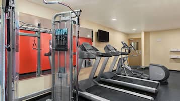 A gym with treadmills, a weight machine, and a mirror.