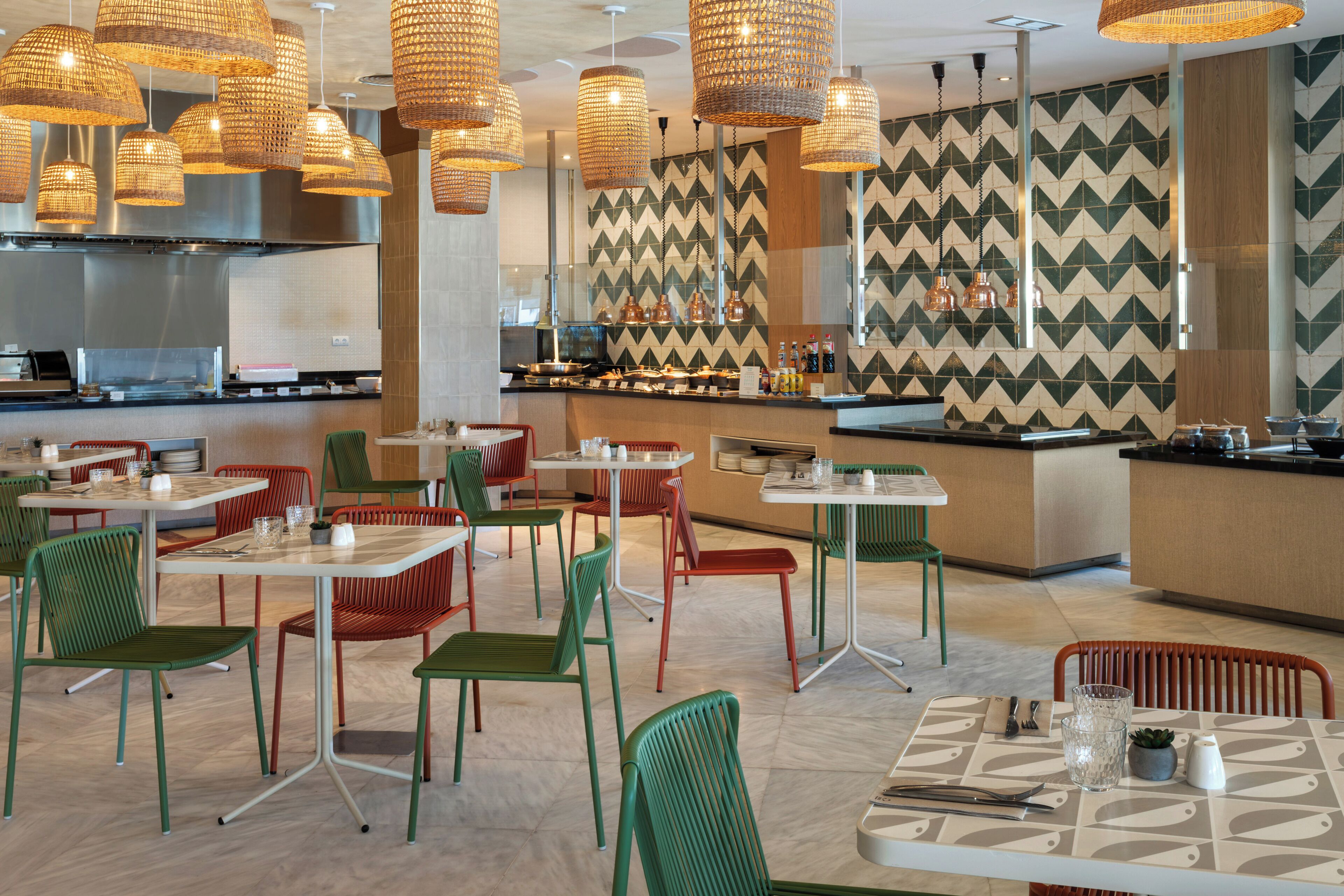 A restaurant with multiple dining tables and chairs, a bar area, and hanging pendant lights.