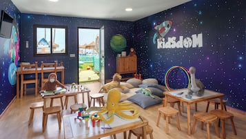 Un cuarto de juegos infantil con un mural de estrellas en la pared, muebles de madera y diversos juguetes.