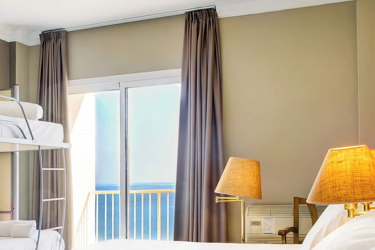 Enjoy ocean views from the balcony of this inviting room, featuring a comfortable bed and a relaxing seating area.