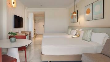 Habitación de hotel con cama, escritorio, silla, televisor y obras de arte en las paredes.