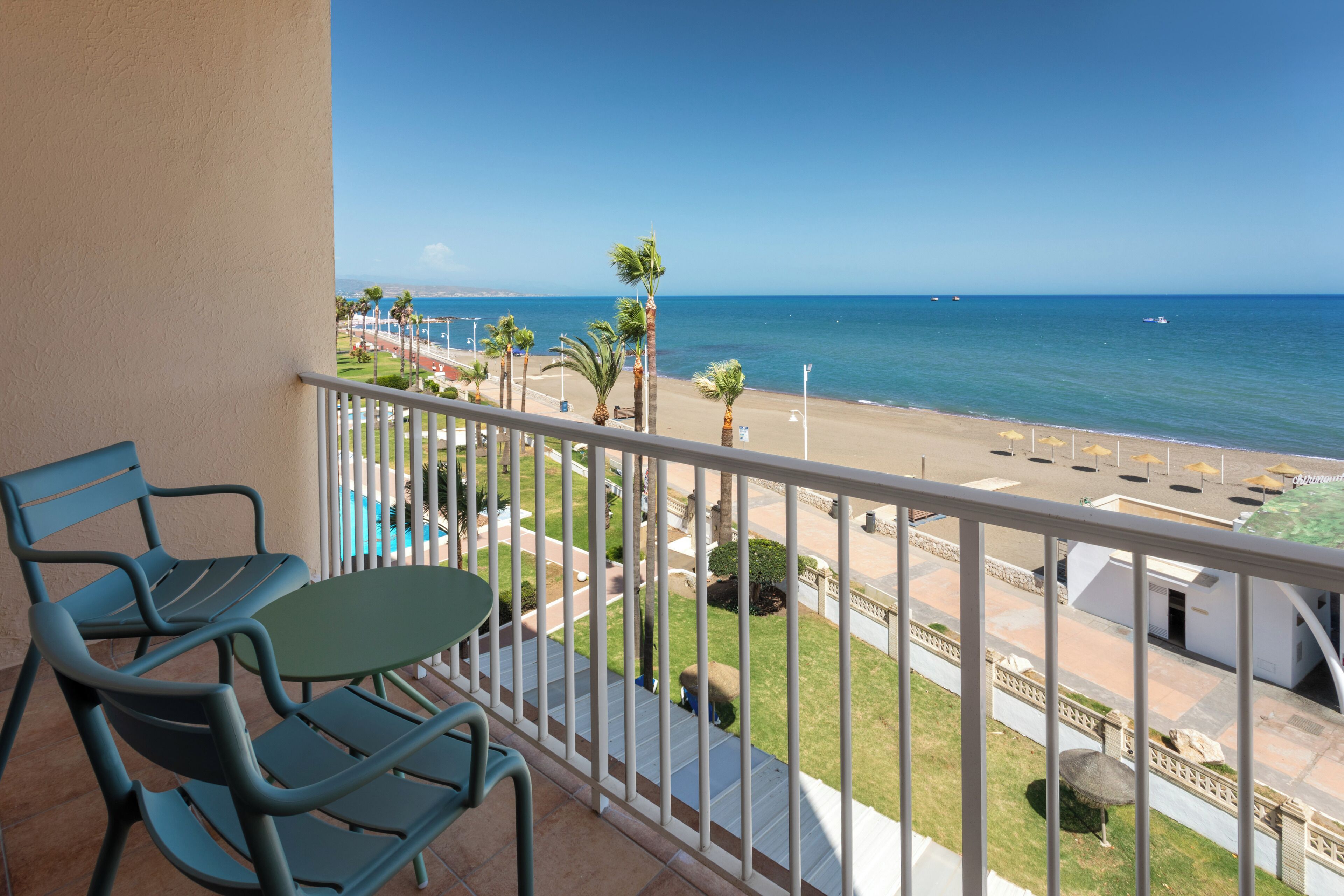 A balcony with a view of a beach and the ocean.