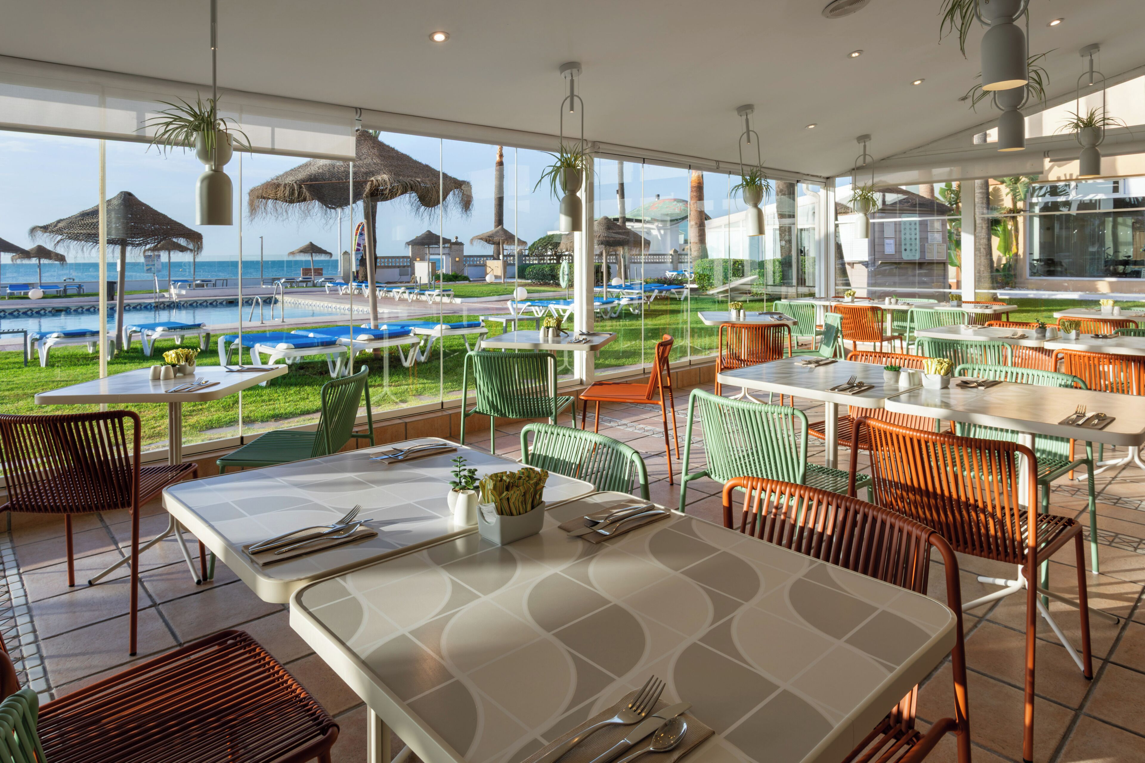 A restaurant with outdoor seating overlooking a pool and beach.