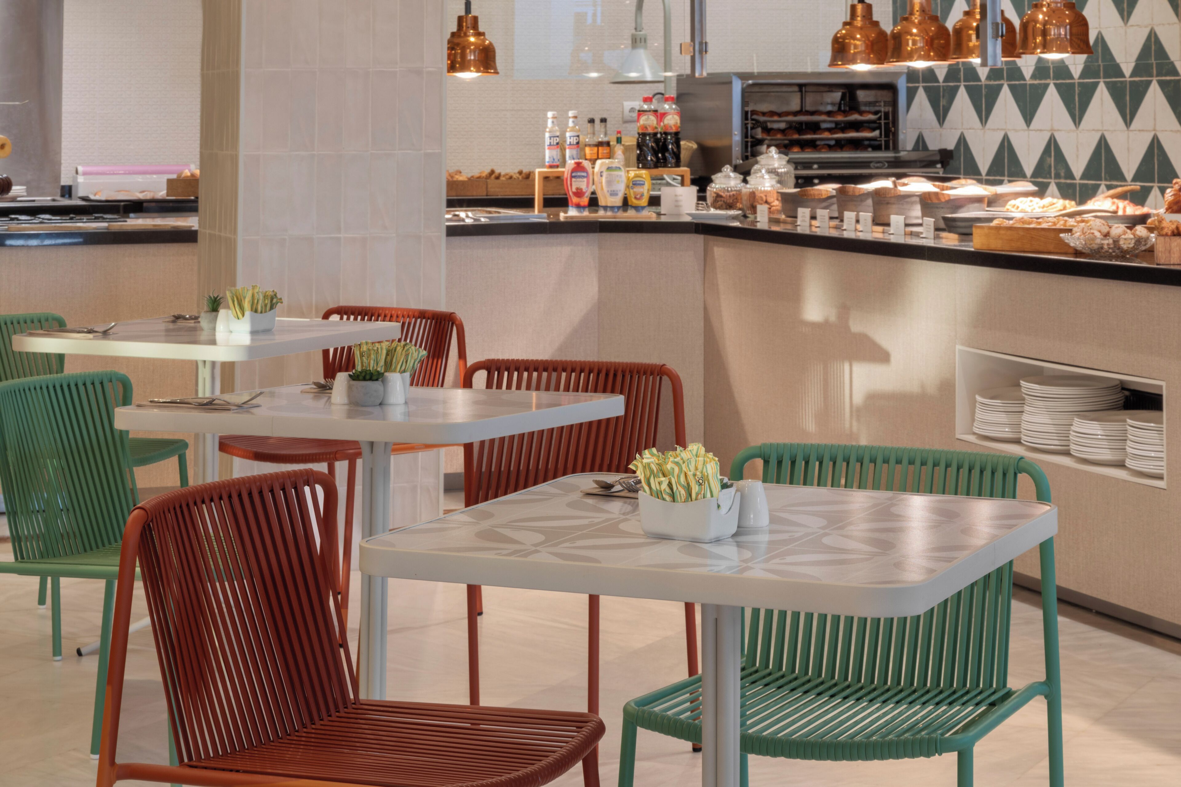 A modern cafe interior with tables, chairs, and a counter displaying food items.