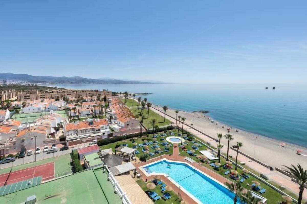 A resort with a swimming pool, beach, tennis courts, and a view of the sea.