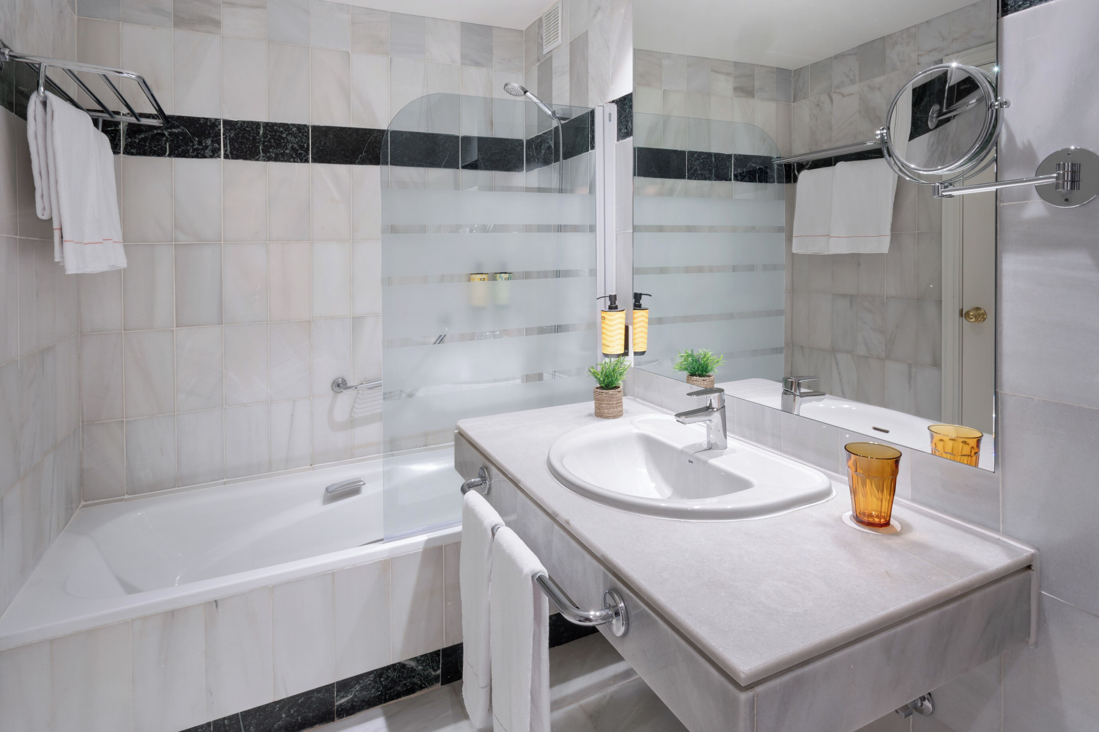 A modern bathroom with a bathtub, a sink, and a mirror.