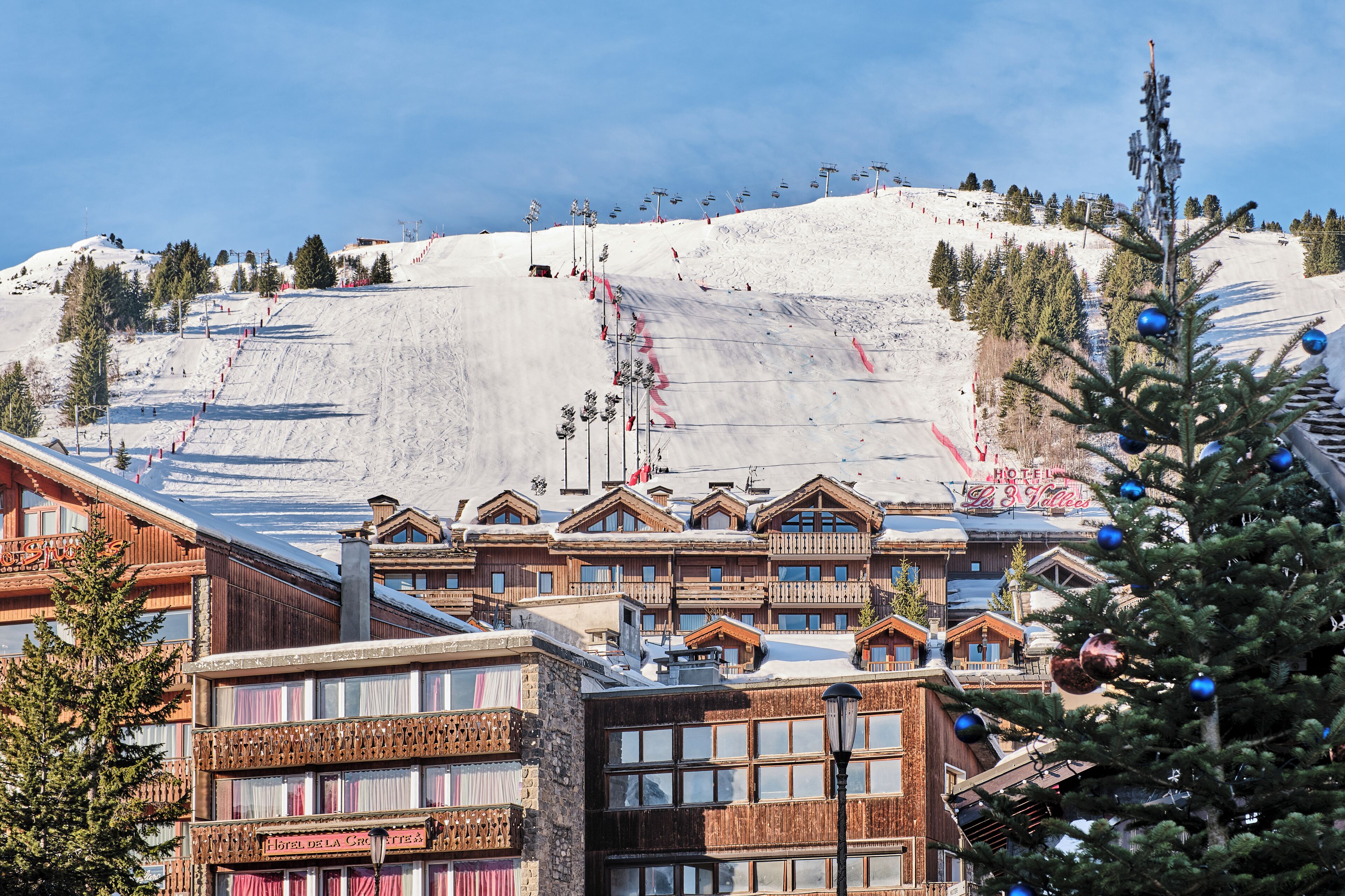 Un centro de esquí con edificios de madera, un telesilla y una ladera cubierta de nieve.