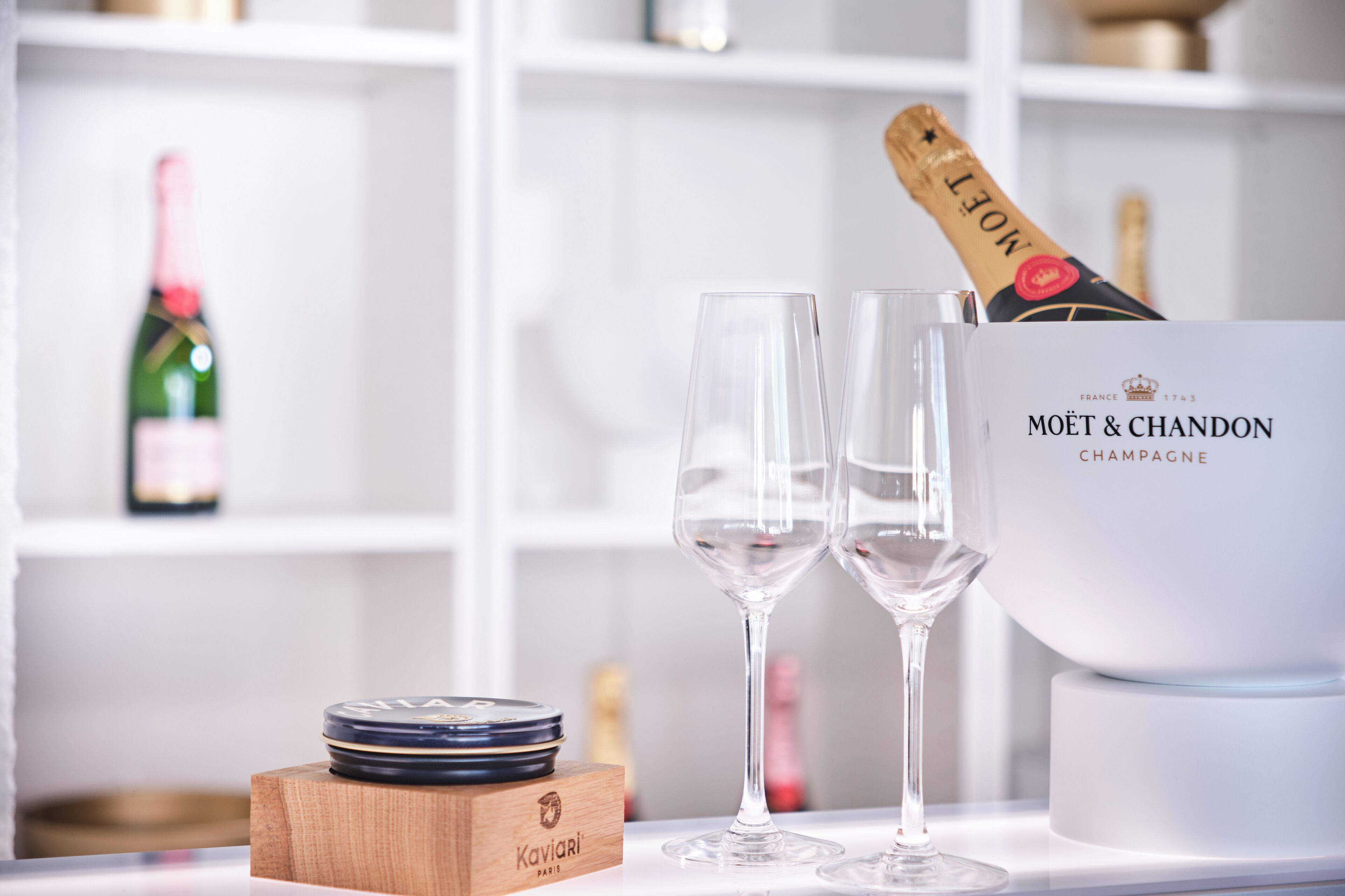 A champagne bottle, two glasses, and a box labeled "MOËT & CHANDON CHAMPAGNE" on a table.