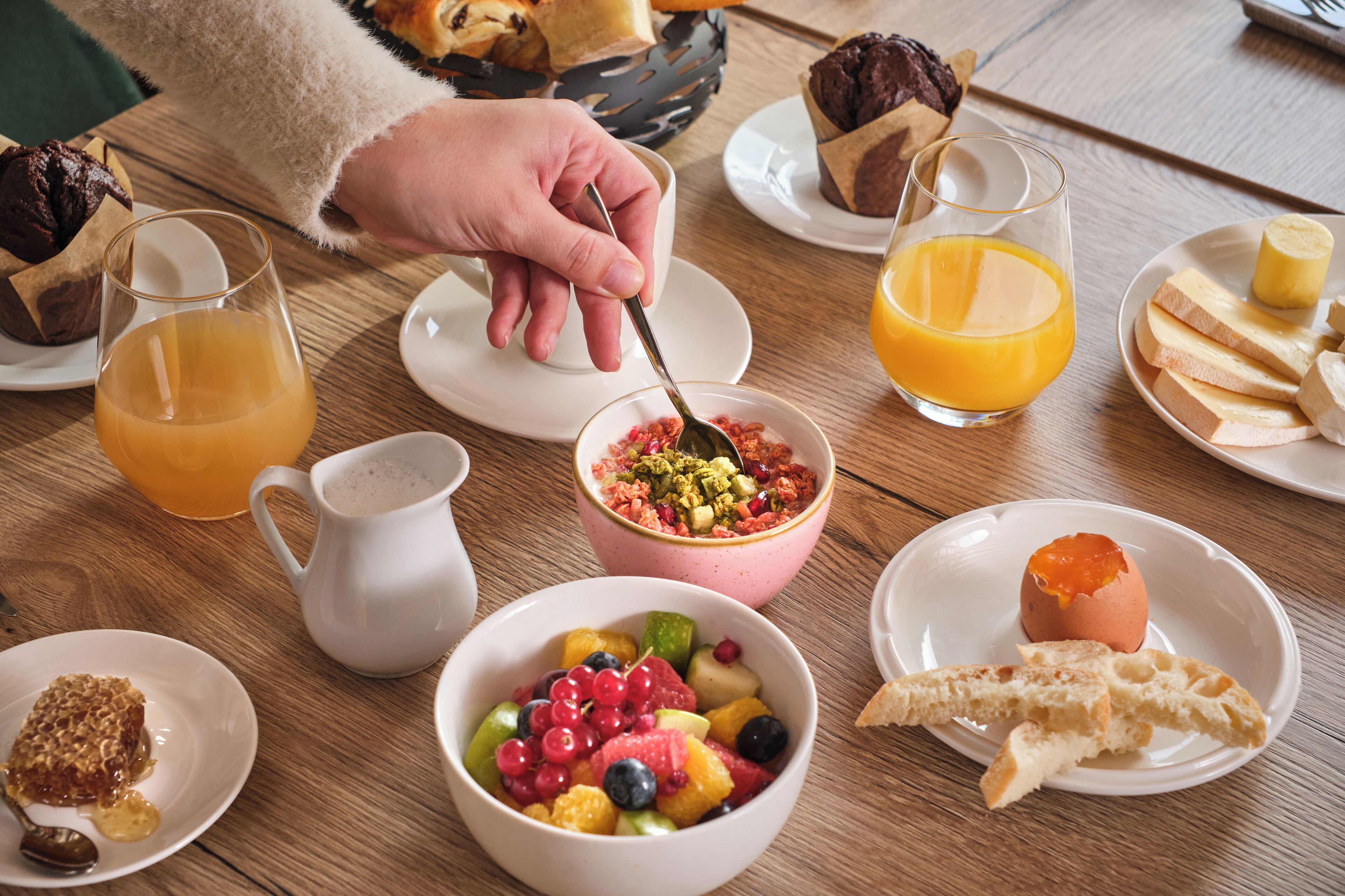 A breakfast table with various dishes including fruit, bread, and a muffin.