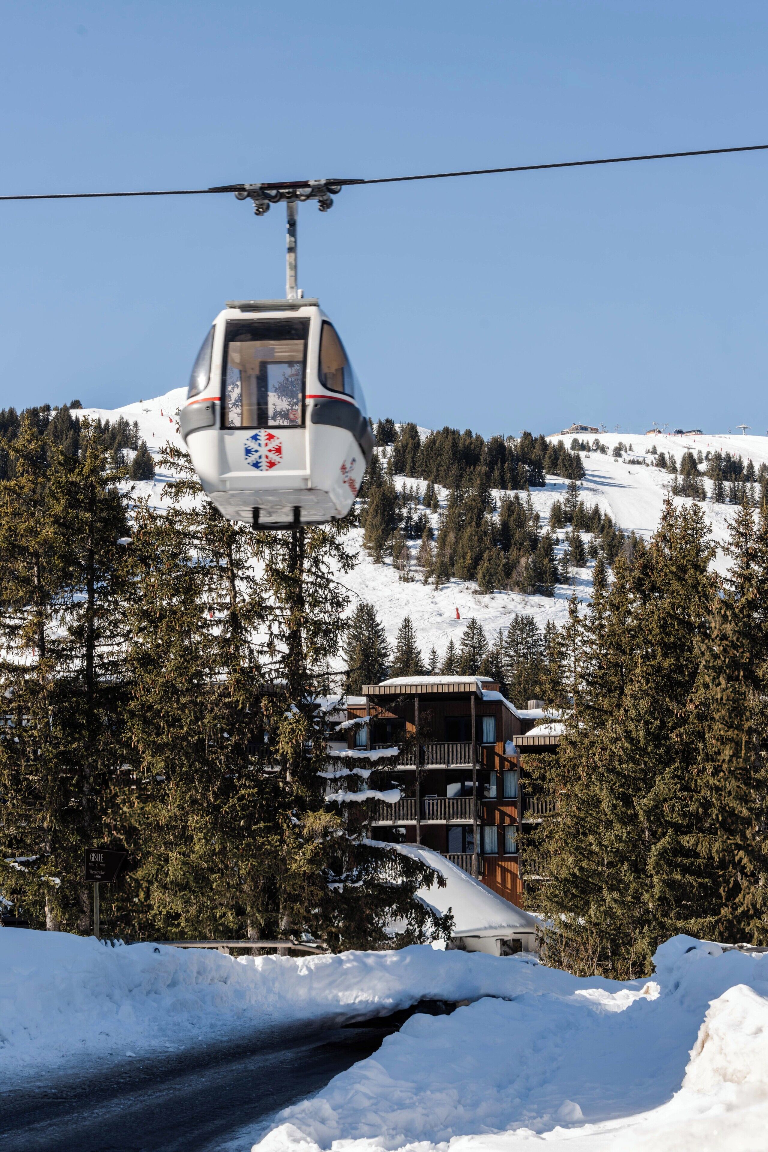 A cable car moving over a snowy landscape with a lodge in the background.