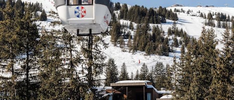 A cable car moving over a snowy landscape with a lodge in the background.
