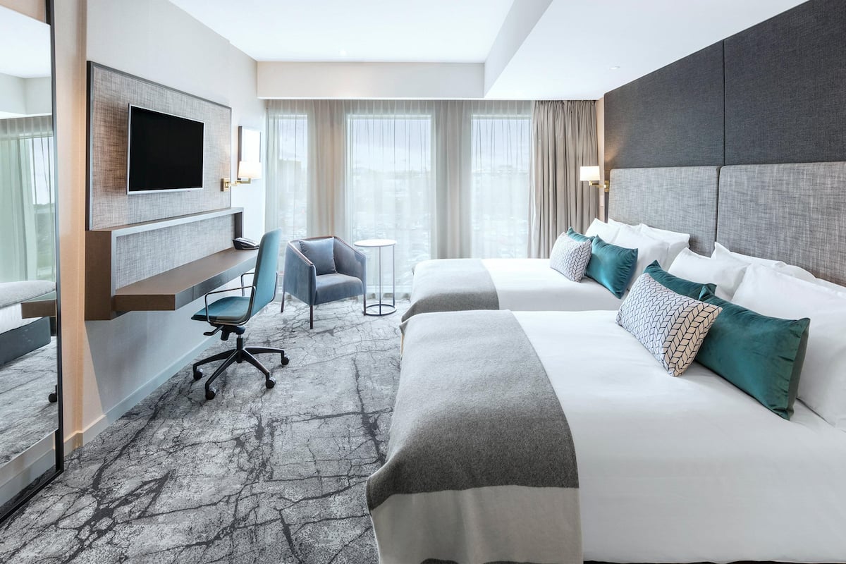 Ein Hotelzimmer mit einem großen Bett, einem Schreibtisch, einem Sessel und einem Fernseher.