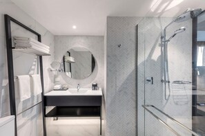 Une salle de bain moderne avec une douche à parois de verre, un miroir rond et un meuble-lavabo noir.