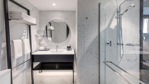 Ein modernes Badezimmer mit einer Dusche in Glaswand, einem runden Spiegel und einem schwarzen Waschtisch.