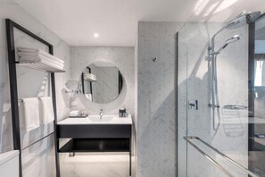 Une salle de bain moderne avec une douche à parois de verre, un miroir rond et un meuble-lavabo noir.
