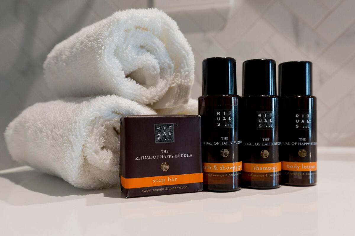 Ein Badezimmer mit Handtuch, Seife und drei Flaschen Shampoo und Körperlotion.