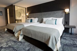 A hotel room with two beds, a glass-enclosed shower, and a bedside table with a lamp. - Crowne Plaza Christchurch (Christchurch)