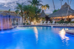 Una piscina al aire libre, sombrillas, sillones reclinables de piscina