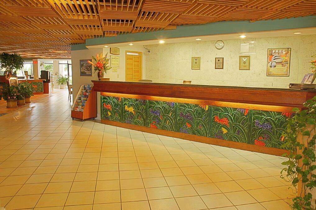 A reception area with a wooden ceiling, tiled floor, and a reception desk with a floral design.