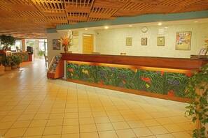 A reception area with a wooden ceiling, tiled floor, and a reception desk with a floral design. - Holiday Inn Key Largo by IHG (Key Largo)