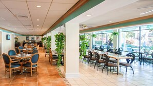A restaurant with indoor seating, a long counter, and large windows.