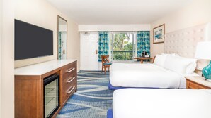 A hotel room with two beds, a TV, a desk, and a window with curtains.