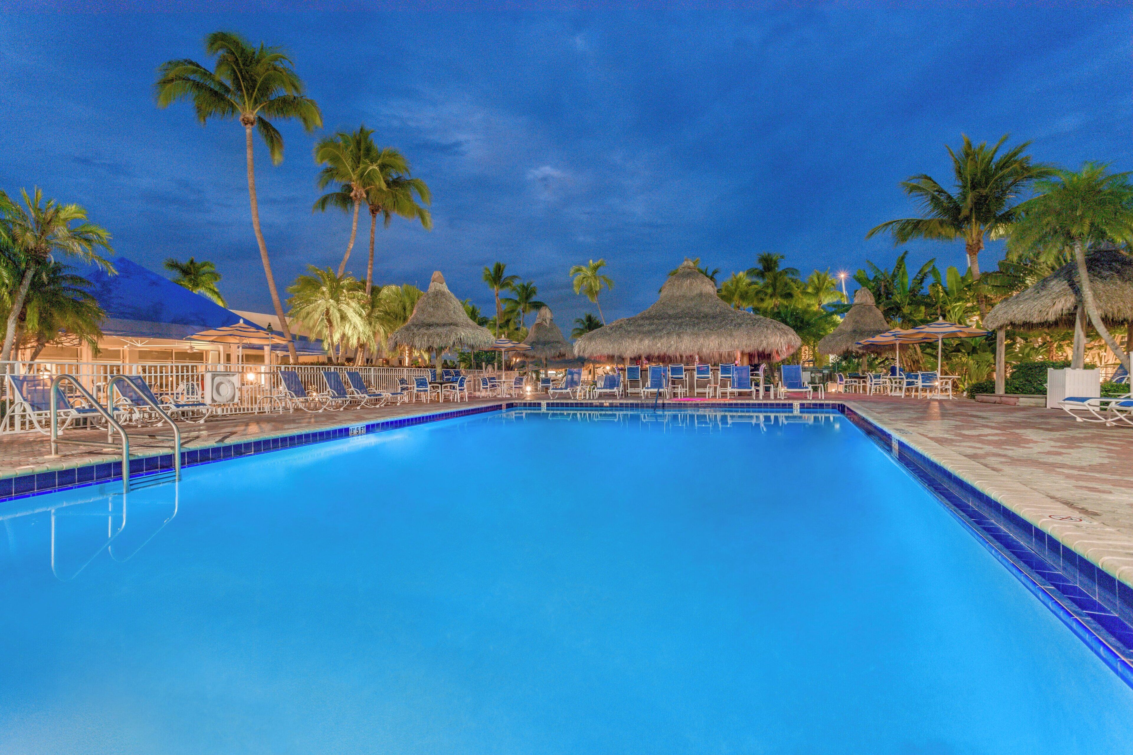 A swimming pool with lounge chairs and palm trees.