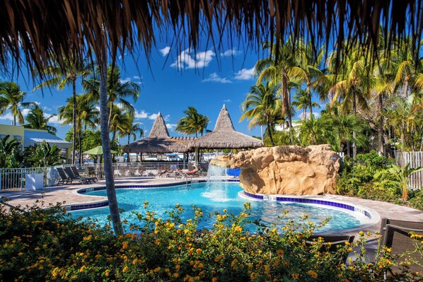 A pool with a rock feature, lounge chairs, and palm trees. - Holiday Inn Key Largo by IHG (Key Largo)