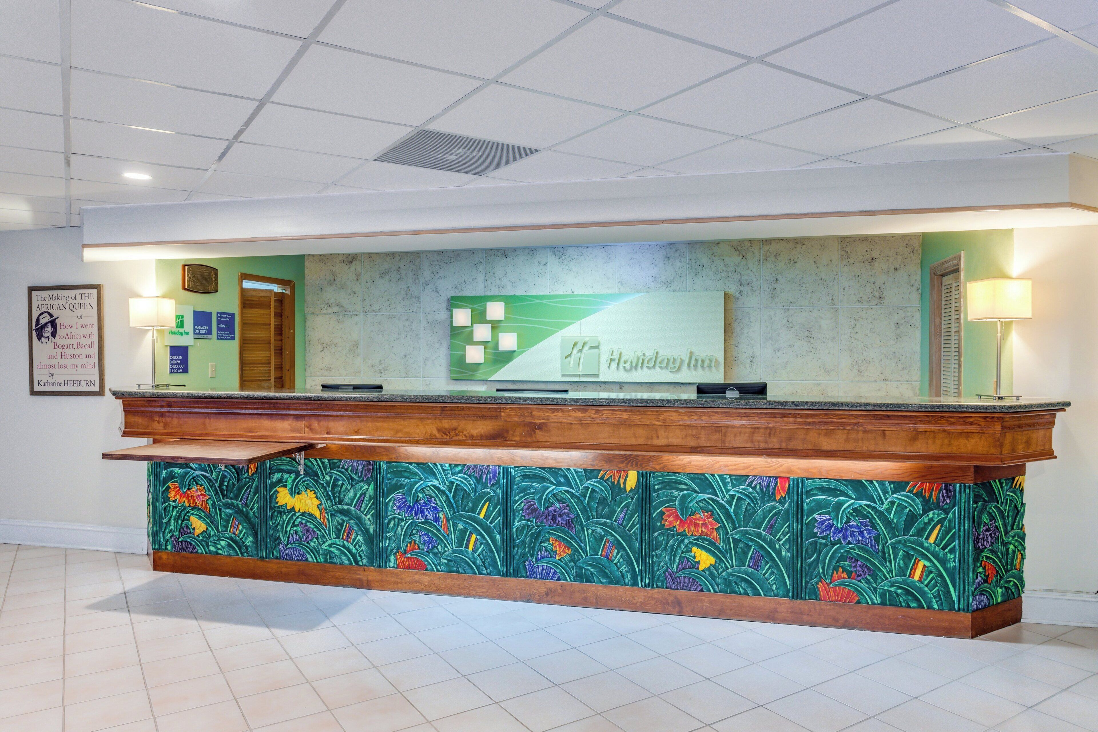 A reception desk with a green and white logo, a framed quote on the wall, and a wooden counter.