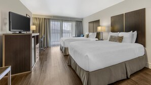 Een hotelkamer met twee bedden, een televisie, een bureau en een raam met gordijnen.