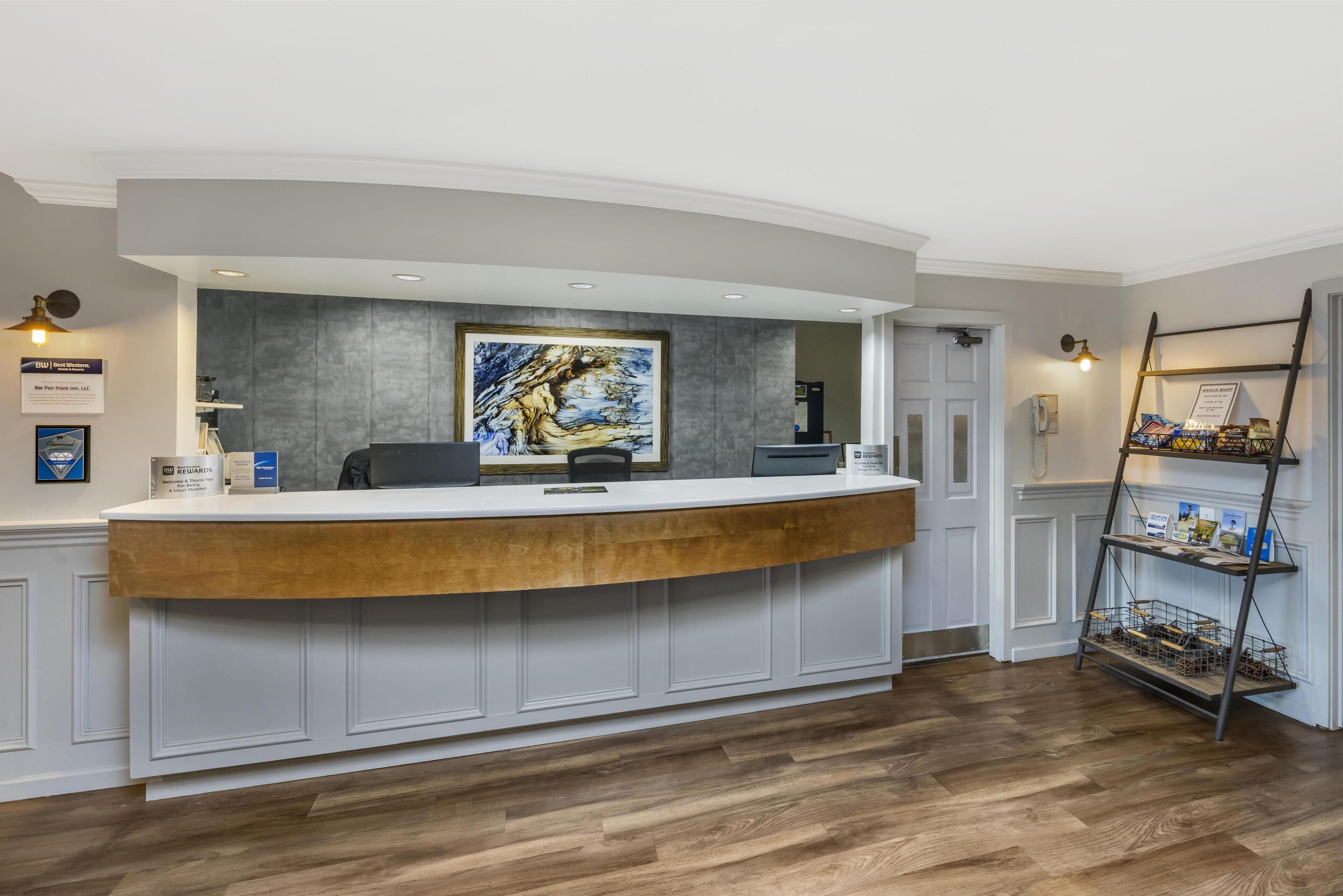 A reception desk with a curved design, a framed artwork above it, and a wooden floor.