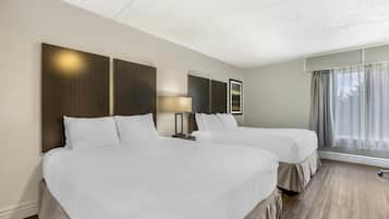 A hotel room with two beds, a nightstand with a lamp, and a large window with curtains.