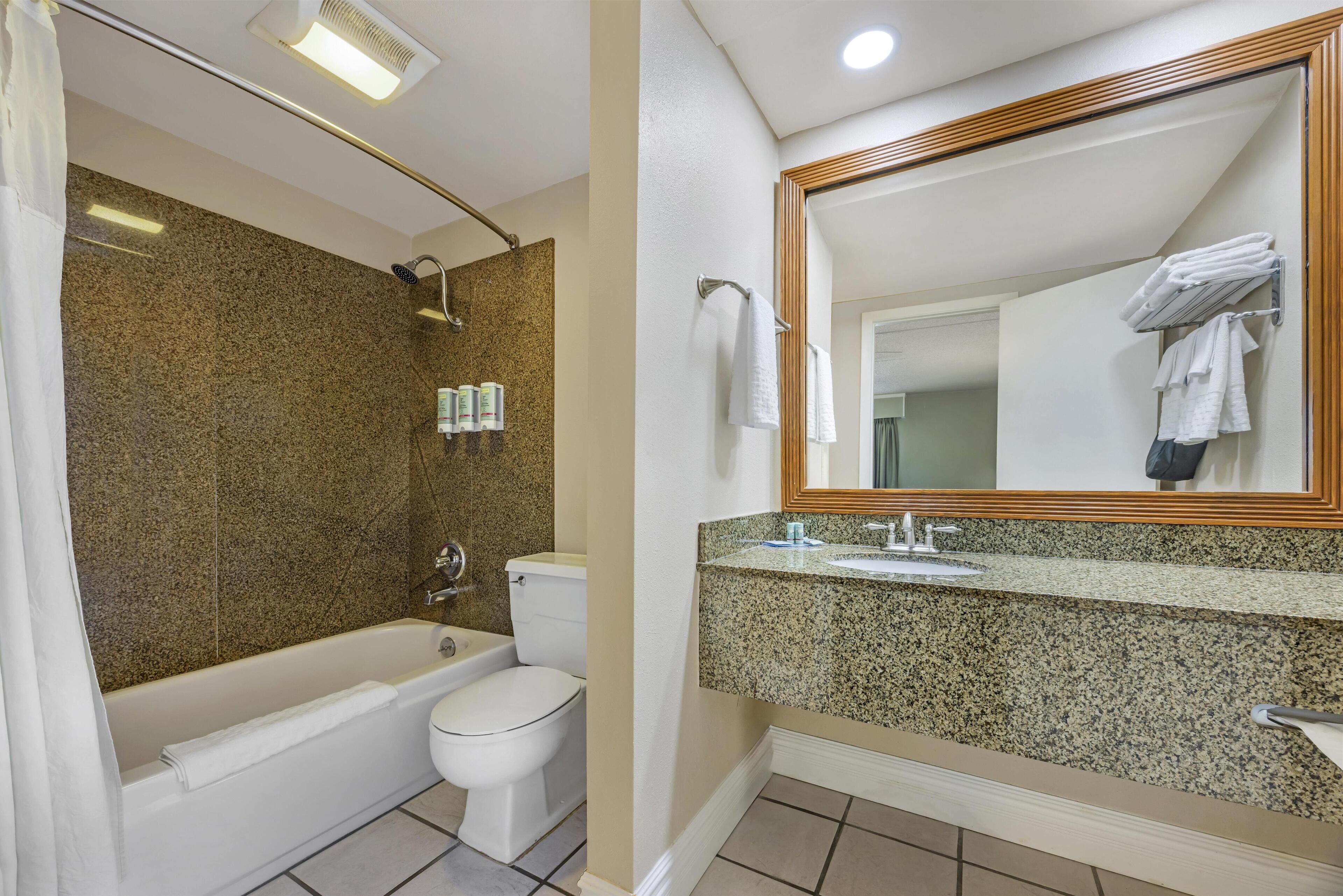 Ein Badezimmer mit Badewanne, Toilette und Waschtisch mit Granitplatte.