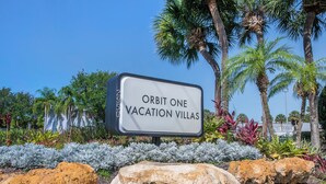 A sign for Orbit One Vacation Villas with a clear view of the surrounding landscaping and palm trees. - Orbit One Vacation Villas by Coolvacay (Kissimmee)