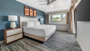 A hotel room with a large bed, a nightstand with a lamp, a ceiling fan, and a window with curtains. - Orbit One Vacation Villas by Coolvacay (Kissimmee)