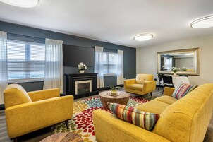 A living room with yellow sofas, a fireplace, and a large mirror.
