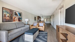 A modern living room with a sofa, armchairs, a coffee table, and a TV. There is a kitchen in the background. - Orbit One Vacation Villas by Coolvacay (Kissimmee)