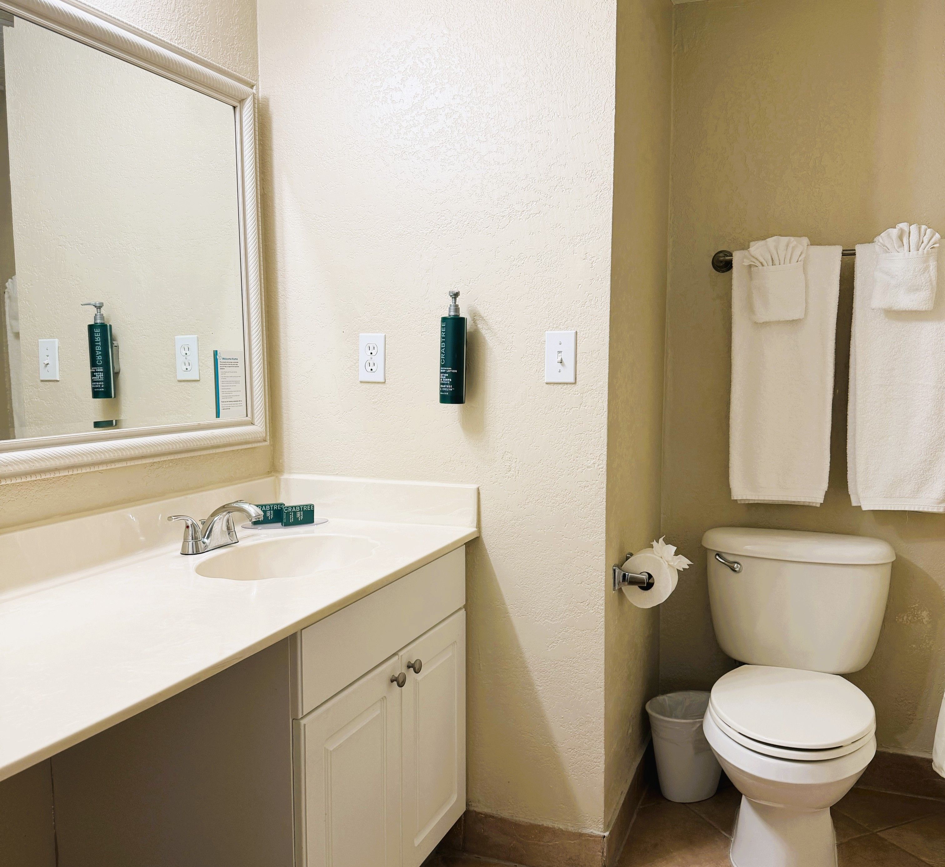 A bathroom with a sink, mirror, toilet, and towel rack.