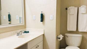 Une salle de bain équipée d’un lavabo, d’un miroir, de toilettes et d’un porte-serviettes.