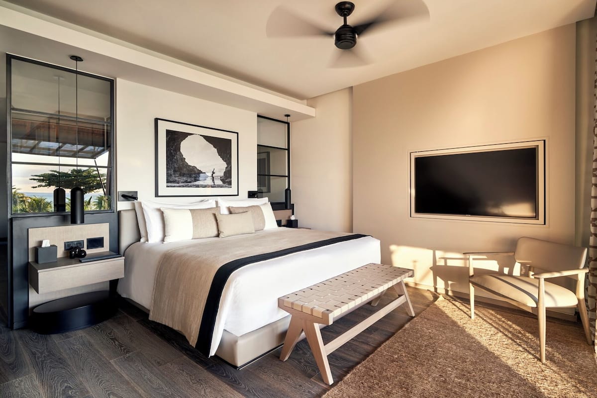 Een moderne hotelkamer met een groot bed, een bureau, een stoel, een televisie en een plafondventilator.
