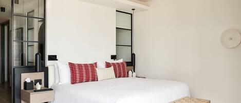 A modern bedroom with a large bed, bedside tables, a bench, and a mirror.