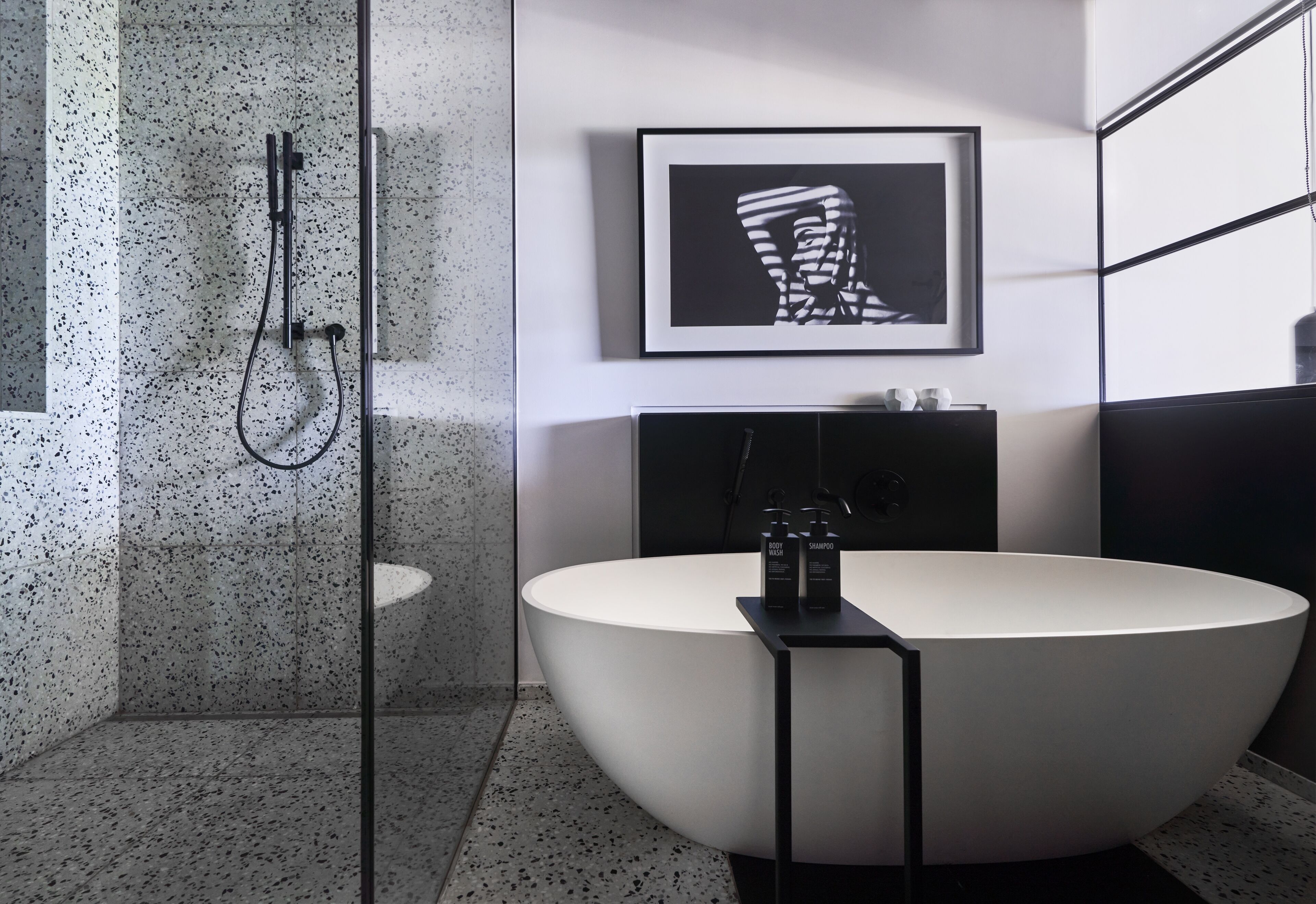 Un bagno moderno con una vasca freestanding, un box doccia in vetro e un quadro appeso alla parete.