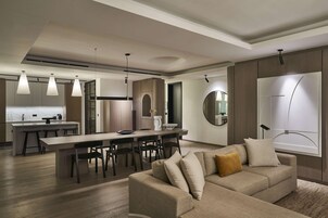 Eine moderne Küche mit Kochinsel, Essbereich und Wohnbereich inklusive Sofa und großem Fenster.